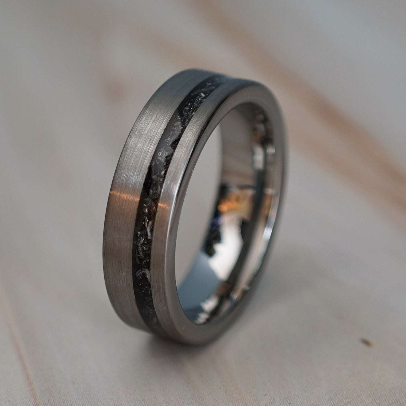 Brushed silver 6mm ring with a black cosmic inlay, engravable, by Forge and Lumber.
