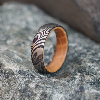 Damascus steel wedding band with artisan forged design and wooden interior, 6mm width.
