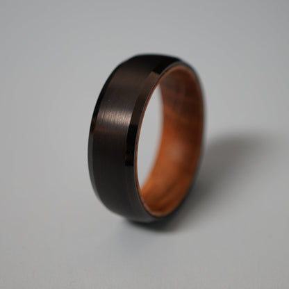Beveled-edge 8mm ring in dark barrel wood by Forge and Lumber, featuring a smooth finish and warm interior.