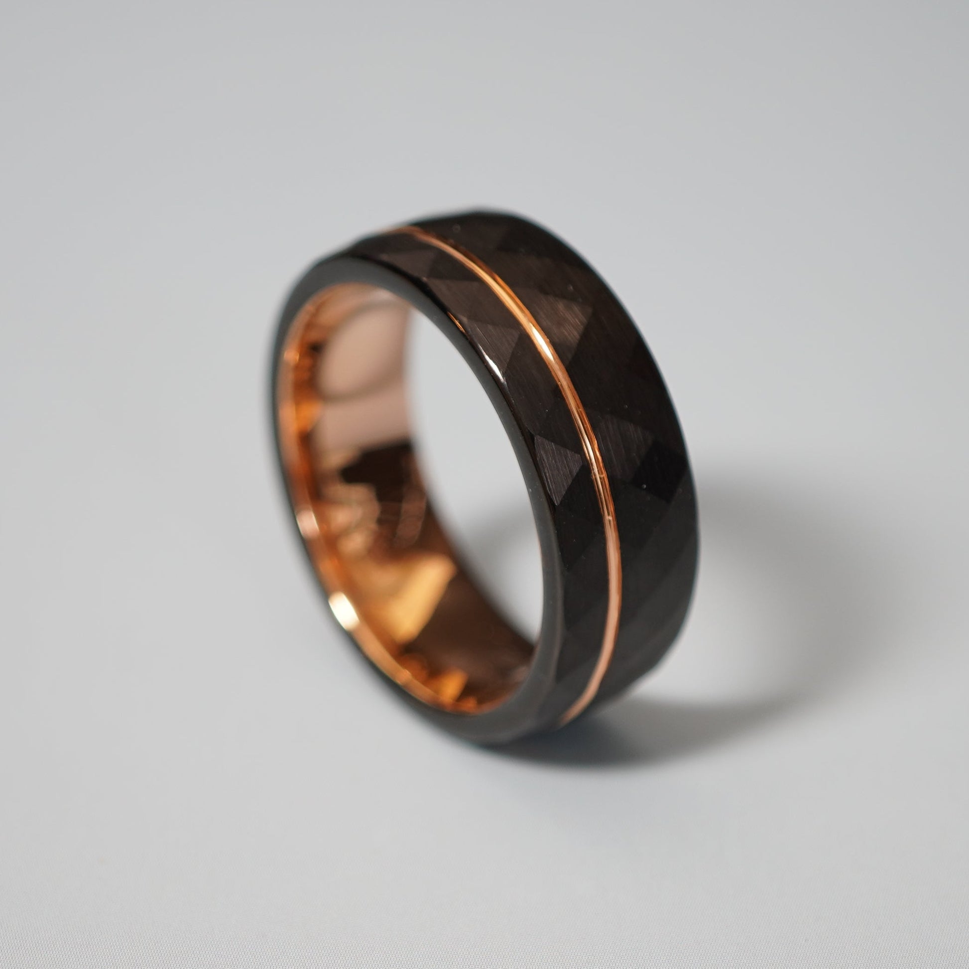 Black active lifestyle ring with a faceted surface and rose gold inlay by Forge and Lumber, 8mm wide.