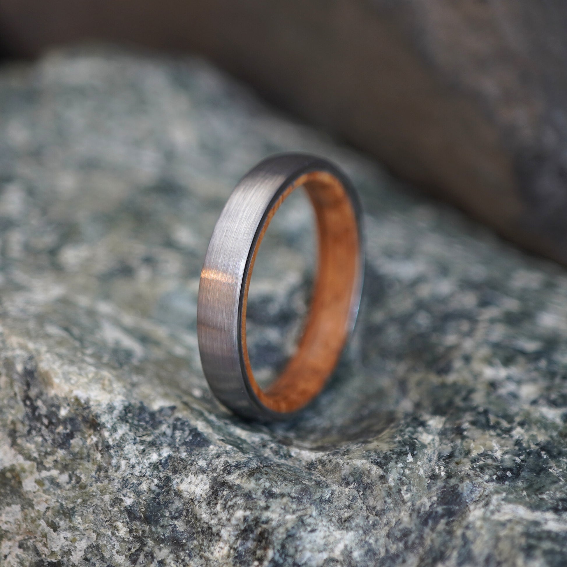 Brushed gray 4mm wedding band with a wooden interior by Forge and Lumber.