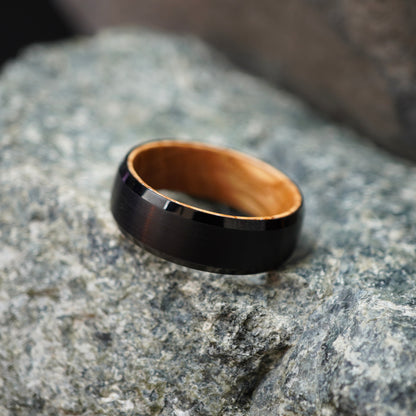 Black beveled-edge ring made from barrel wood by Forge and Lumber, showcasing a polished exterior and natural wood interior.