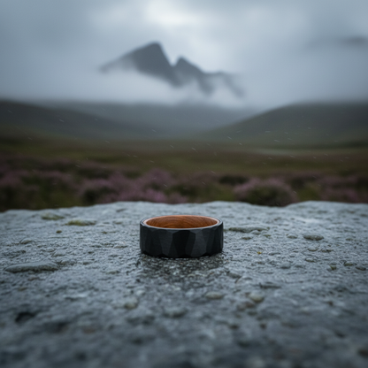 Black and wooden 8mm anniversary ring from Forge and Lumber, set against a misty mountain backdrop.