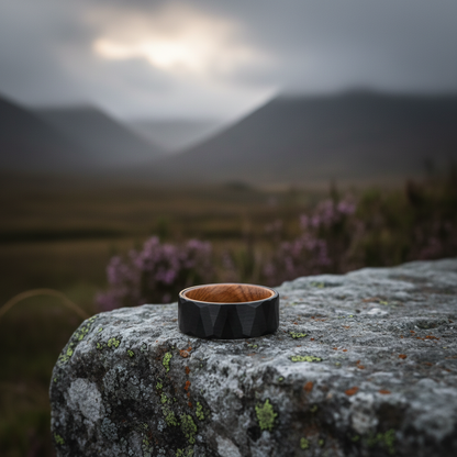 8mm black anniversary ring with wood inlay by Forge and Lumber, resting on a mossy stone outdoor backdrop