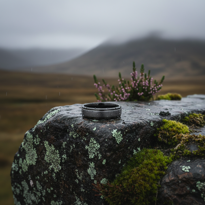 Beveled tungsten wedding band in black, featuring a matte finish, resting on a moss-covered rock in nature.