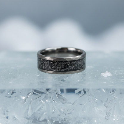 Black alternative metal wedding band with celestial design, by Forge and Lumber, showcased on icy surface.