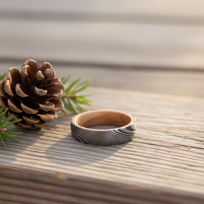 Damascus steel wedding band with artisan forged design and wooden interior, available from Forge and Lumber.