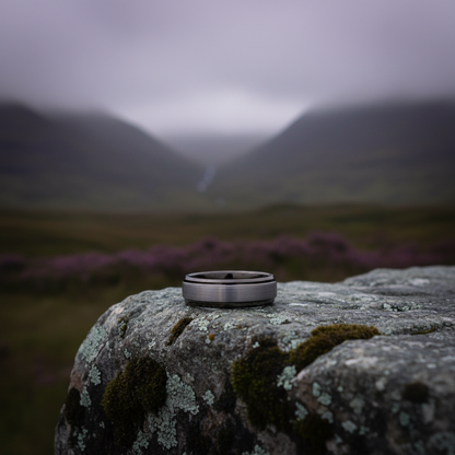 Forge and Lumber 6mm wedding band with a sleek metal finish, set against a natural rocky background.